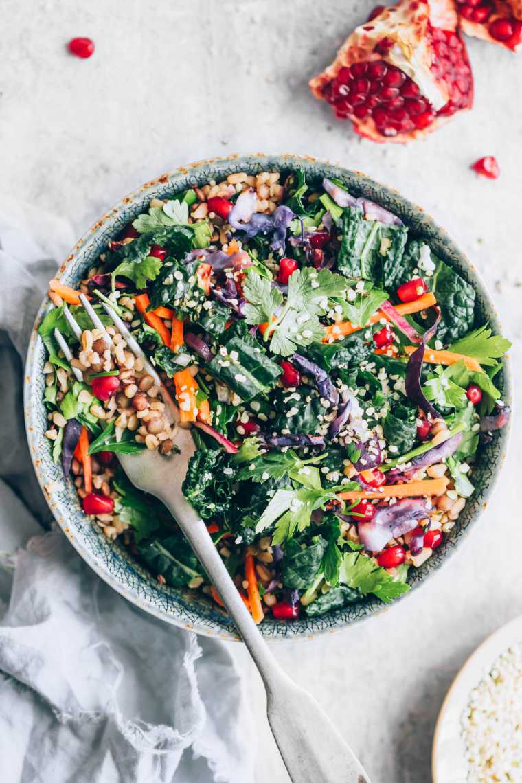 bowl of colorful vegan kale winter salad with lentils, bulgur and a fork