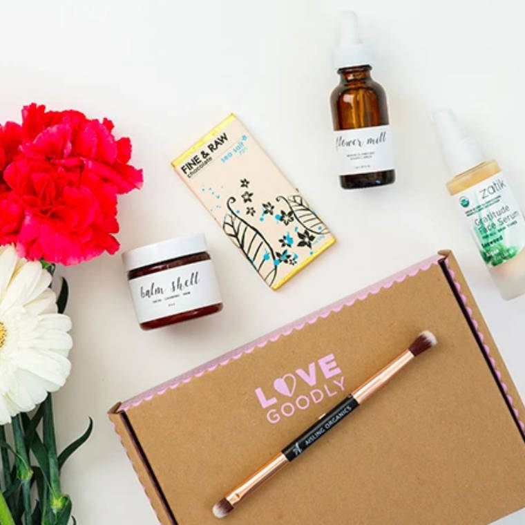 white table with several vegan cosmetic products and a carton saying love goodly
