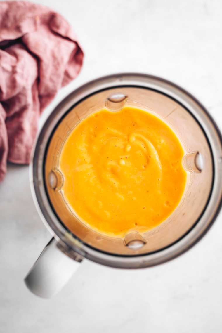 blender jar with bright orange mango smoothie