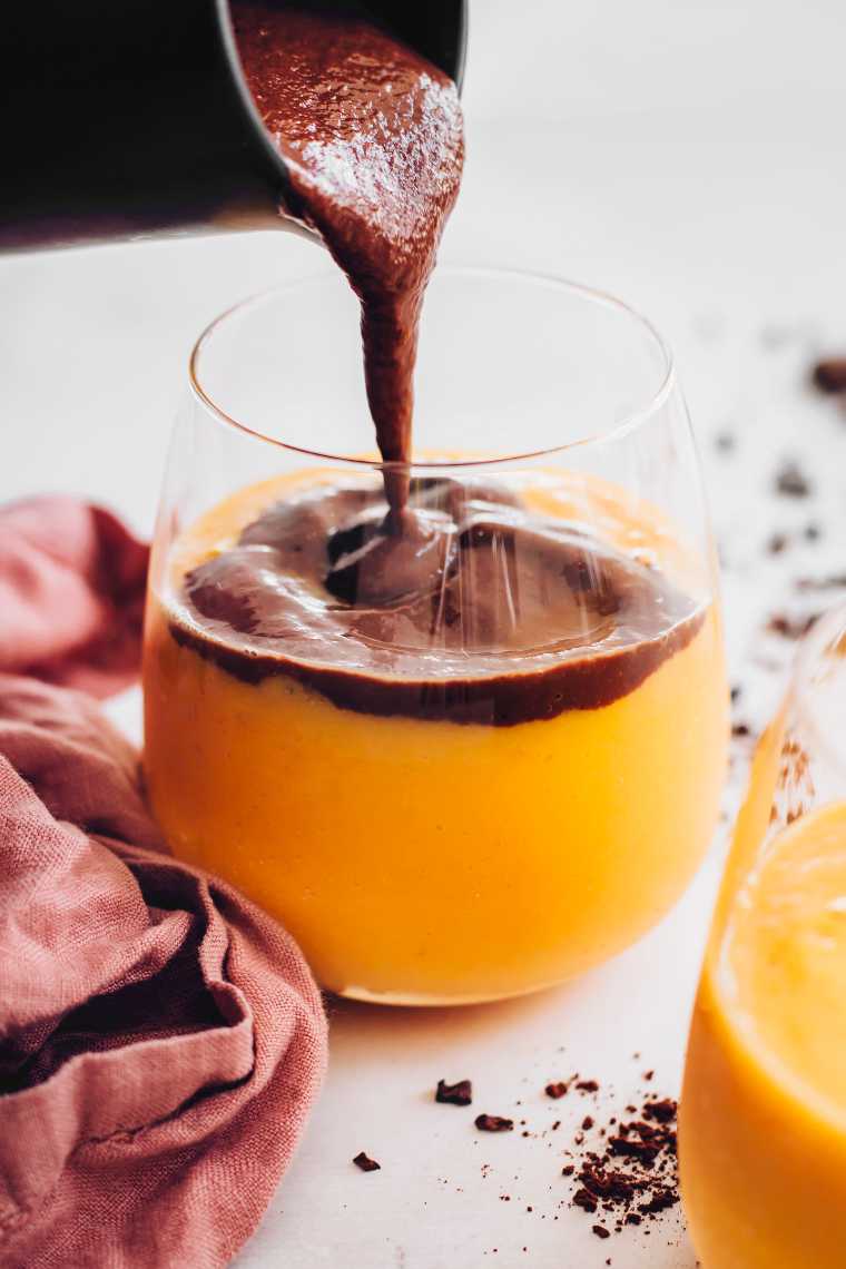glass with mango smoothie being poured with chocolate smoothie