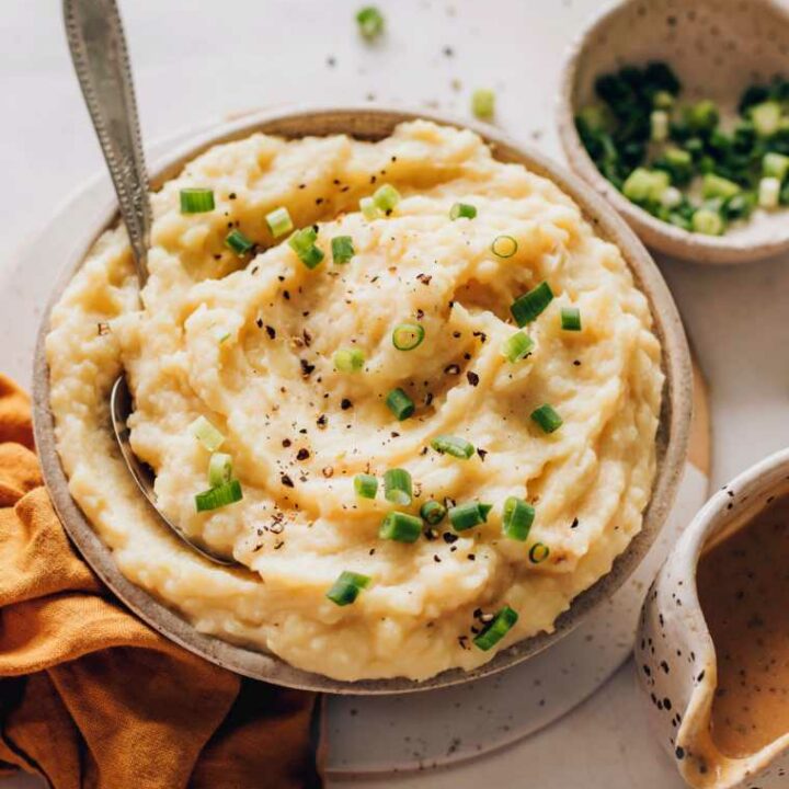 table with a bowl of plant-based mashed potatoes decorated with black pepper and green onion