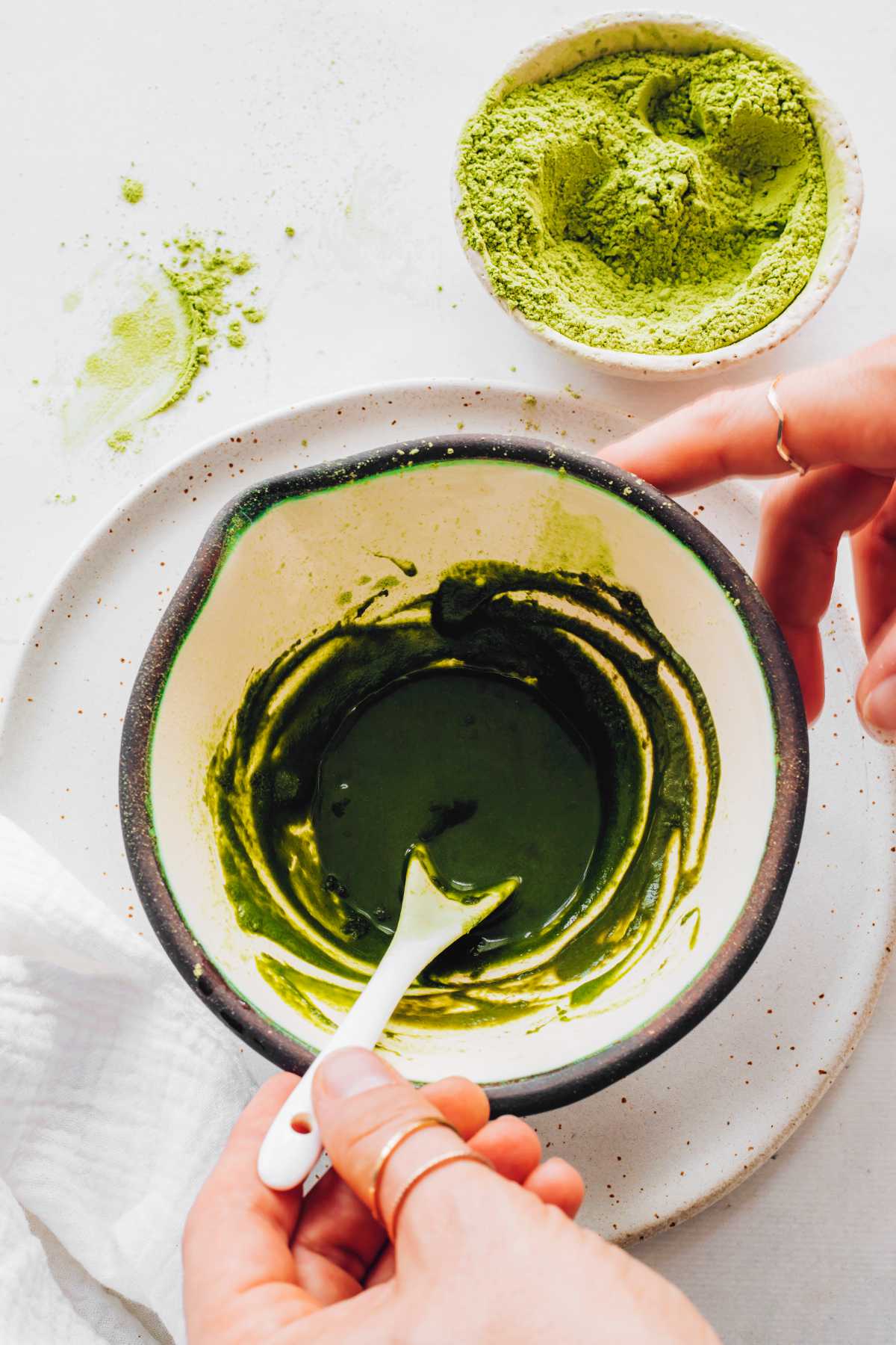 mixing matcha powder with water in a small bowl