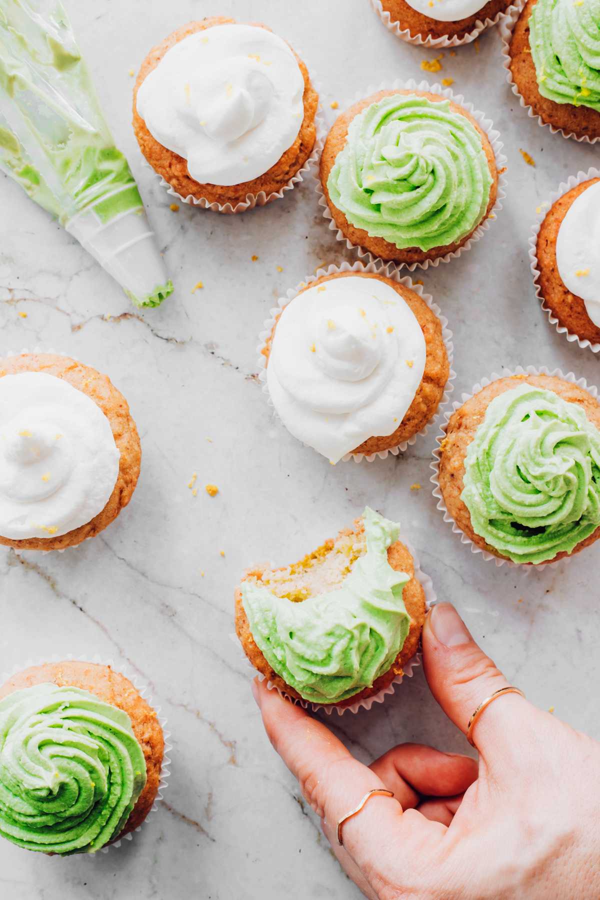 several vegan cupcakes with lemon and matcha frosting on a table