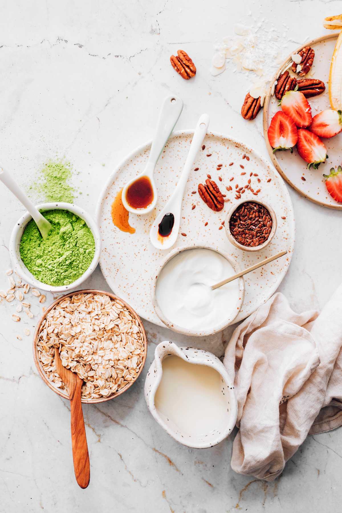 oats, matcha, nuts, seeds, and plant-based milk on a table