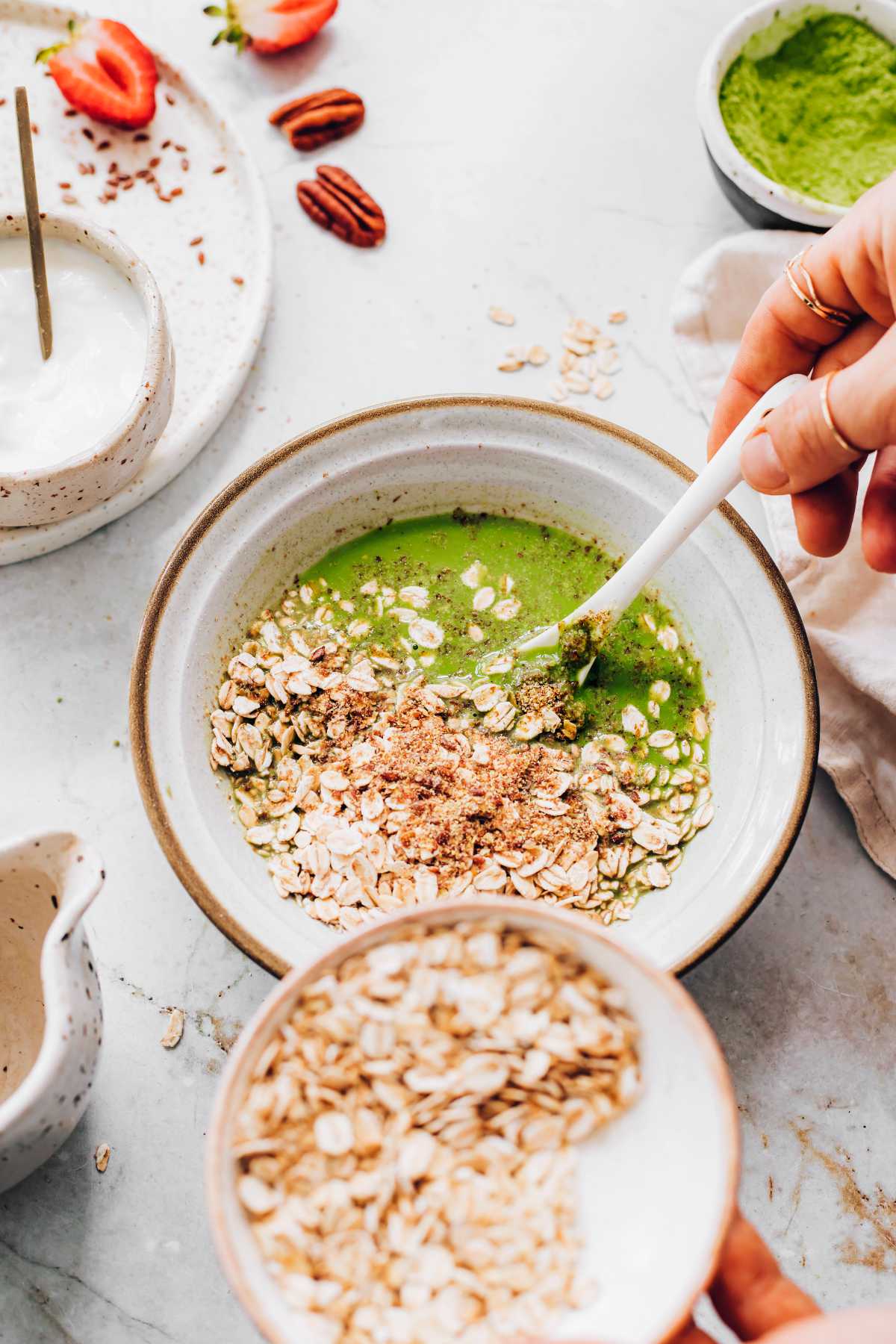adding oats to matcha milk mixture with a spoon