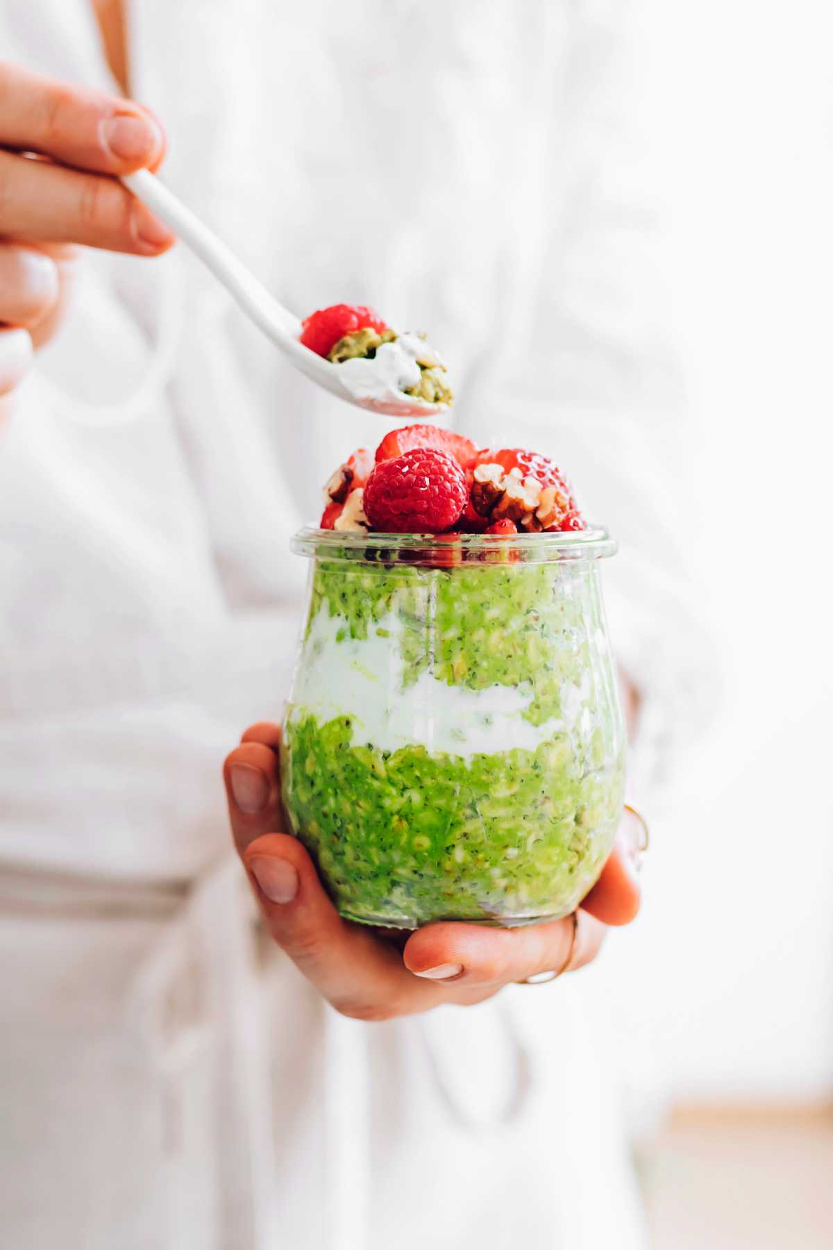 holding a jar of matcha oats with berries
