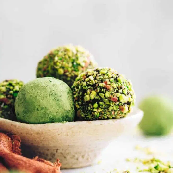 small bowls on a table with 5 matcha pistachio bliss balls