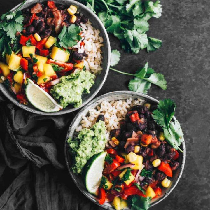 two Mexican Buddha Bowls, cilantro and a towel on a table