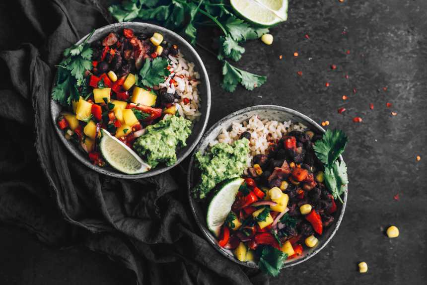 two Mexican Buddha Bowls with lime and cilantro on a table