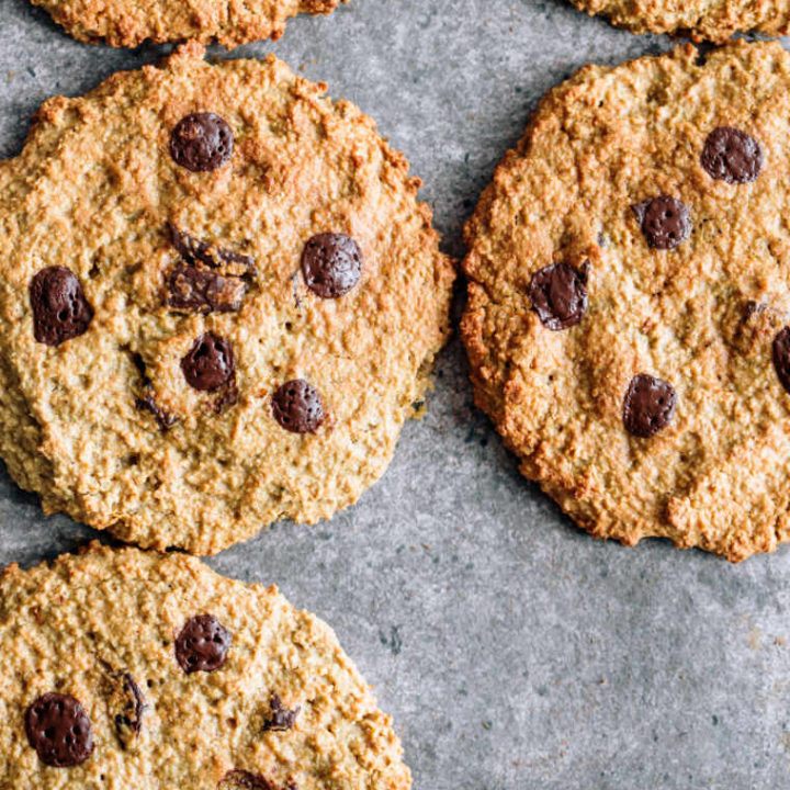 five gluten-free vegan oatmeal cookies with chocolate chips on grey surface