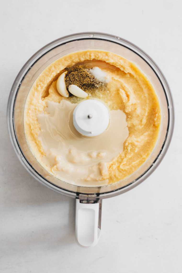 food processor with blended chickpeas, garlic, spices and tahini