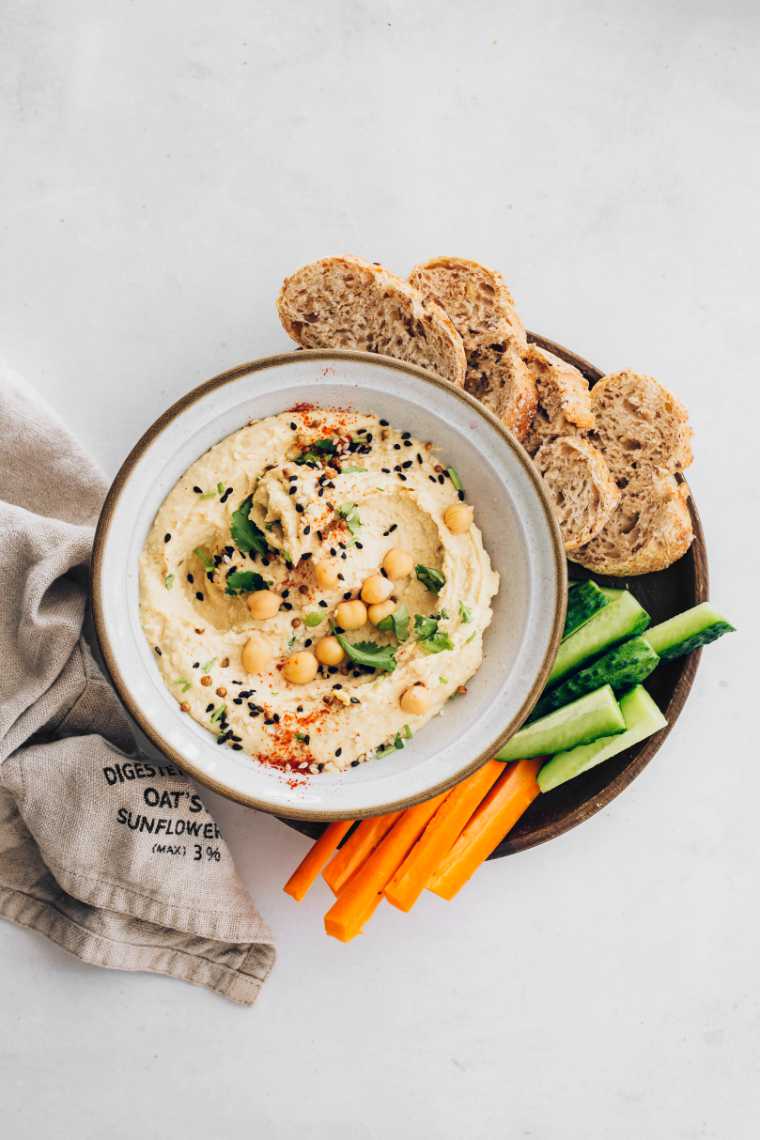 plate with carrots, cucumber, sliced bread and a bowl of homemade vegan hummus