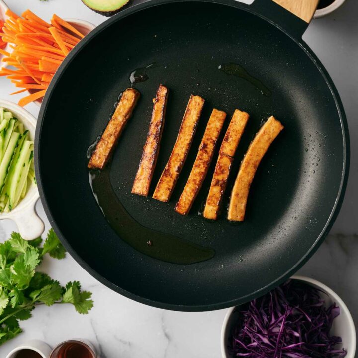 Frying Tofu in a pan next to veggies