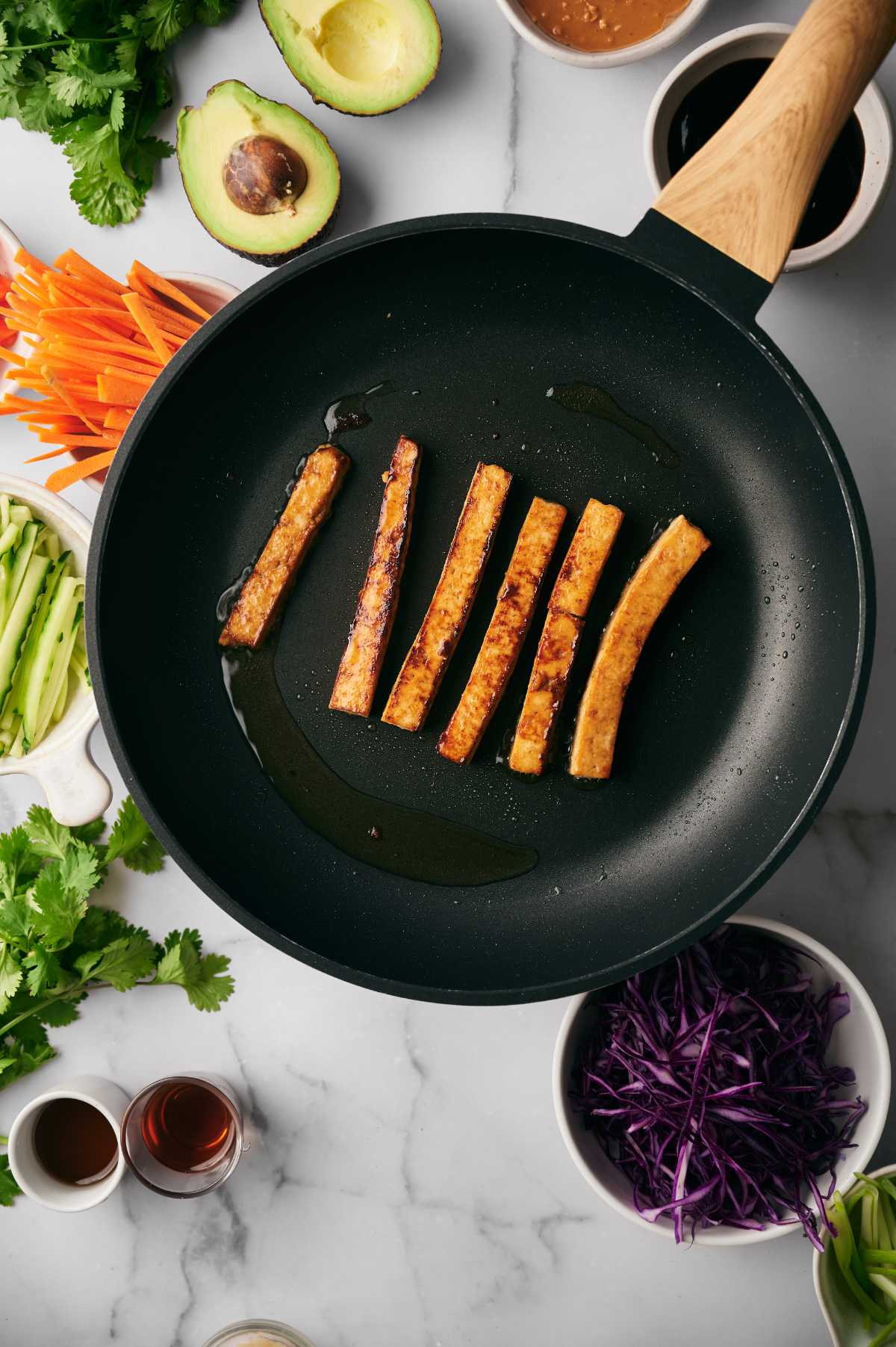 Frying Tofu in a pan next to veggies