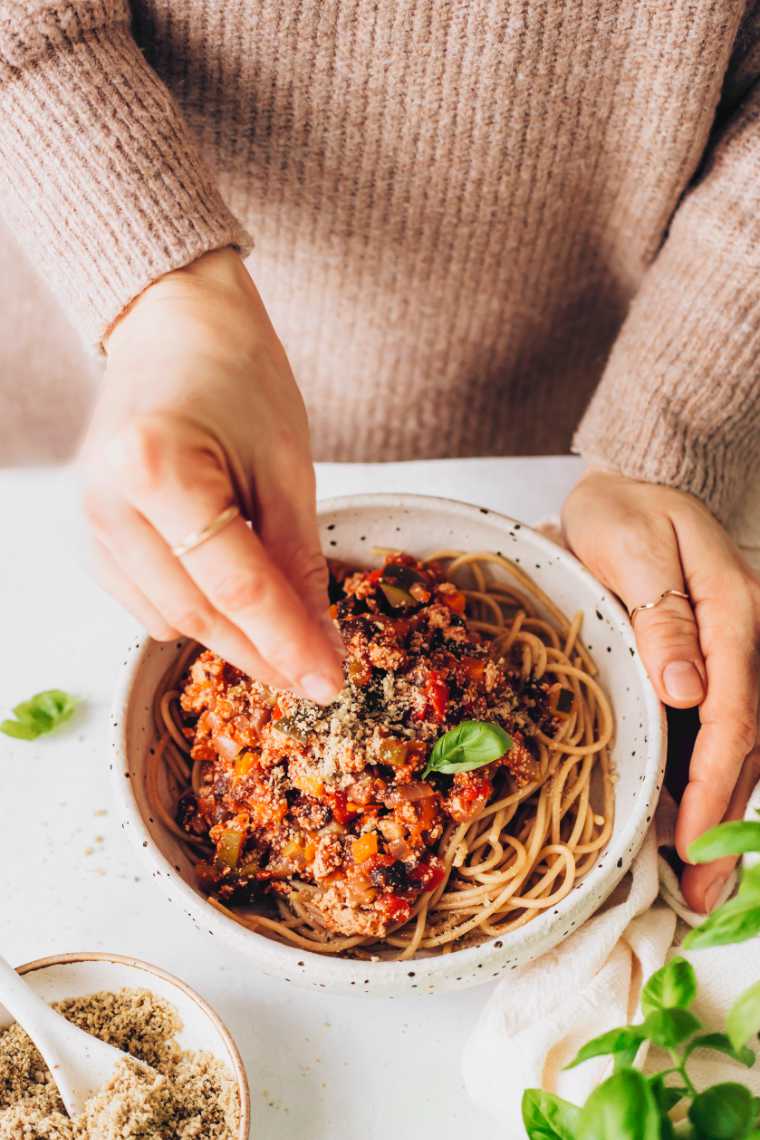 topping bolognese with vegan parmesan