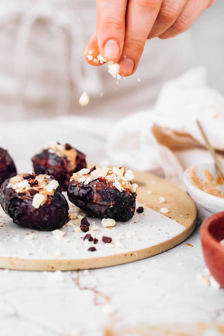 hand sprinkling chopped nuts on stuffed dates
