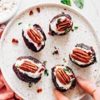 hand reaching for a pecan stuffed date on a place with more dates