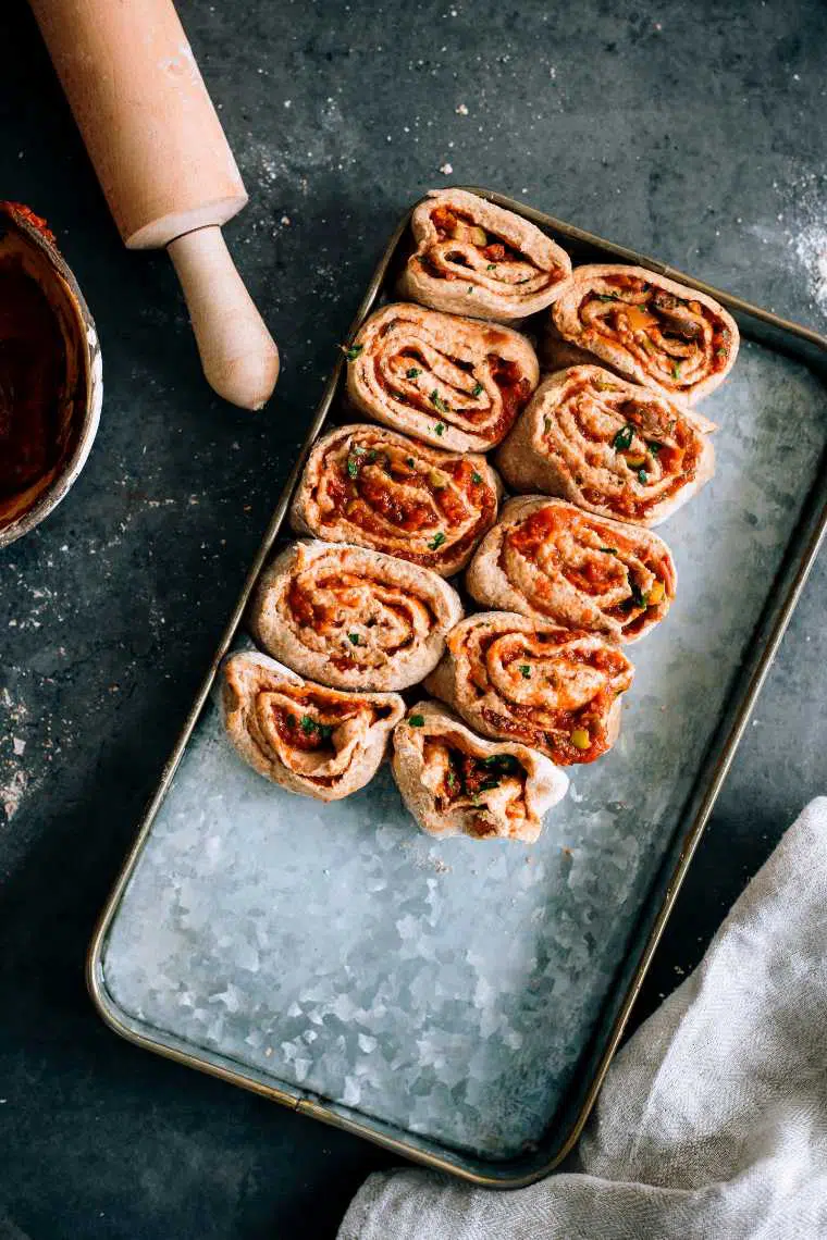 rustic baking dish filled with ten vegan pizza rolls that are about to be baked