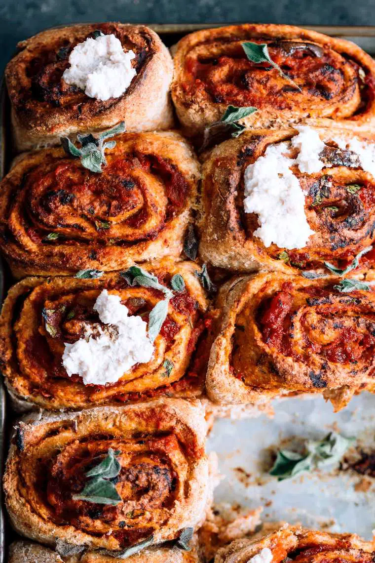 close up of seven freshly baked tomatoey vegan pizza buns with almond ricotta topping