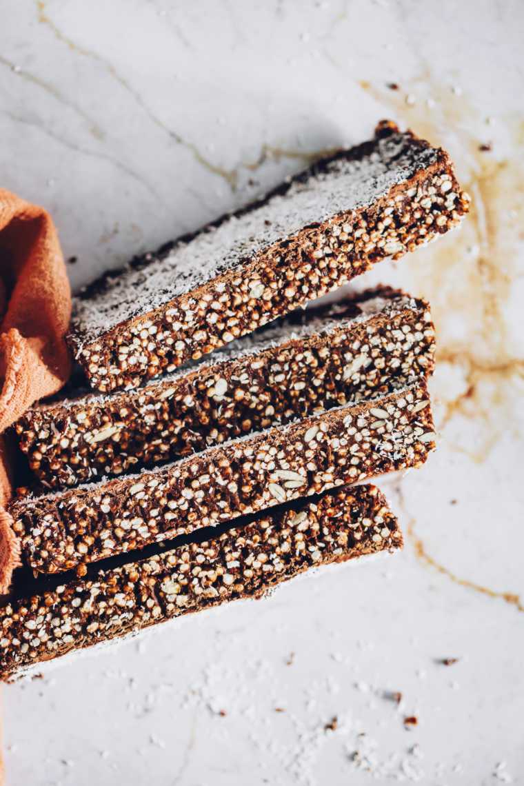 four slices of chocolate quinoa bars topped with coconut shreds on a white table