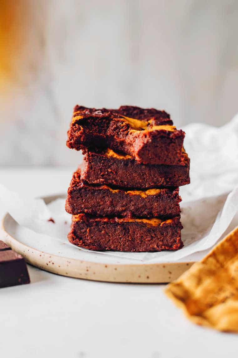 four fudgy pumpkin brownies on top of each other on a plate