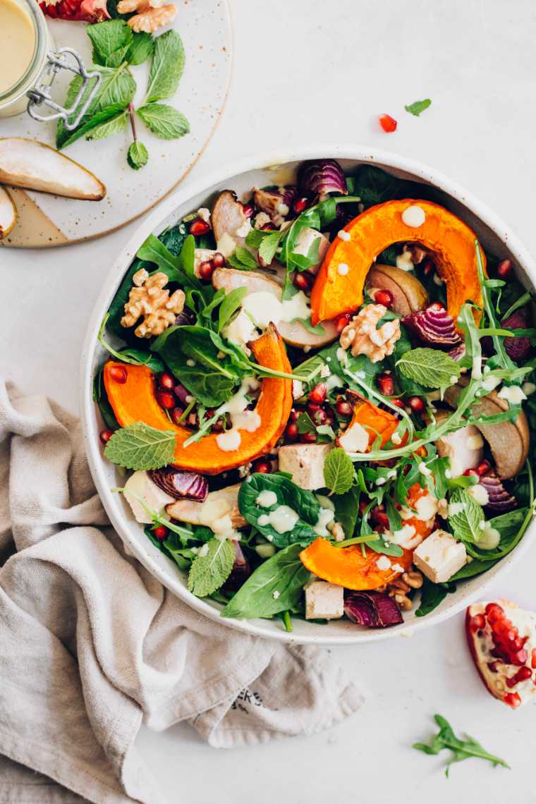 large bowl with pumpkin, spinach and feta salad next to a towel
