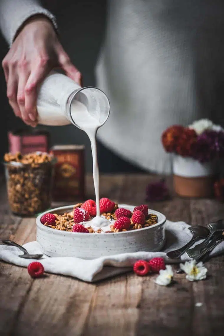 vegan Christmas breakfast spread on a wooden table with a pumpkin granola and raspberries in the foreground