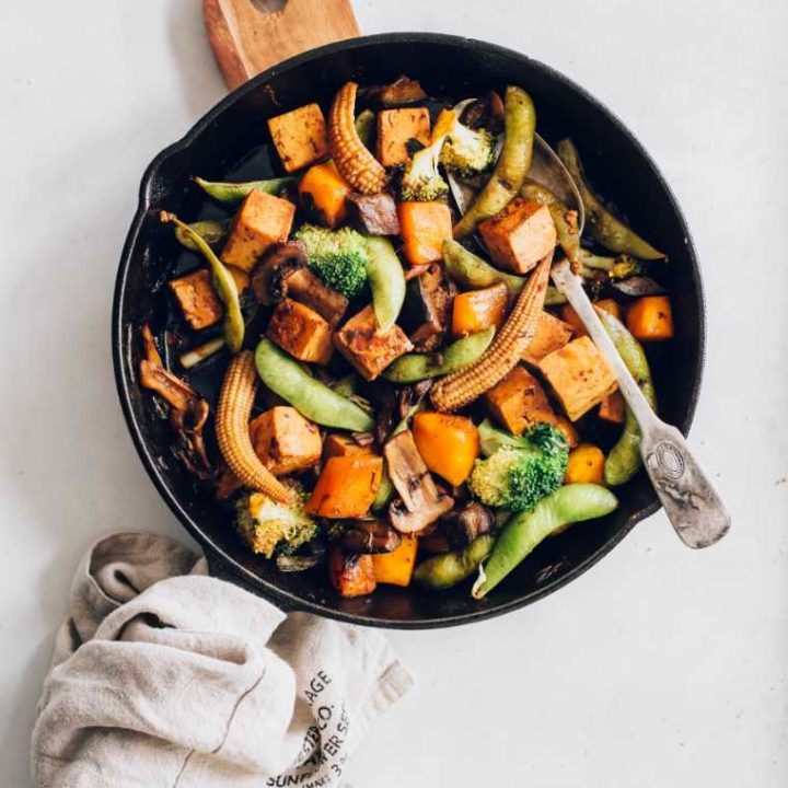 back pan on a chopping board with freshly cooked pumpkin stir fried vegetables