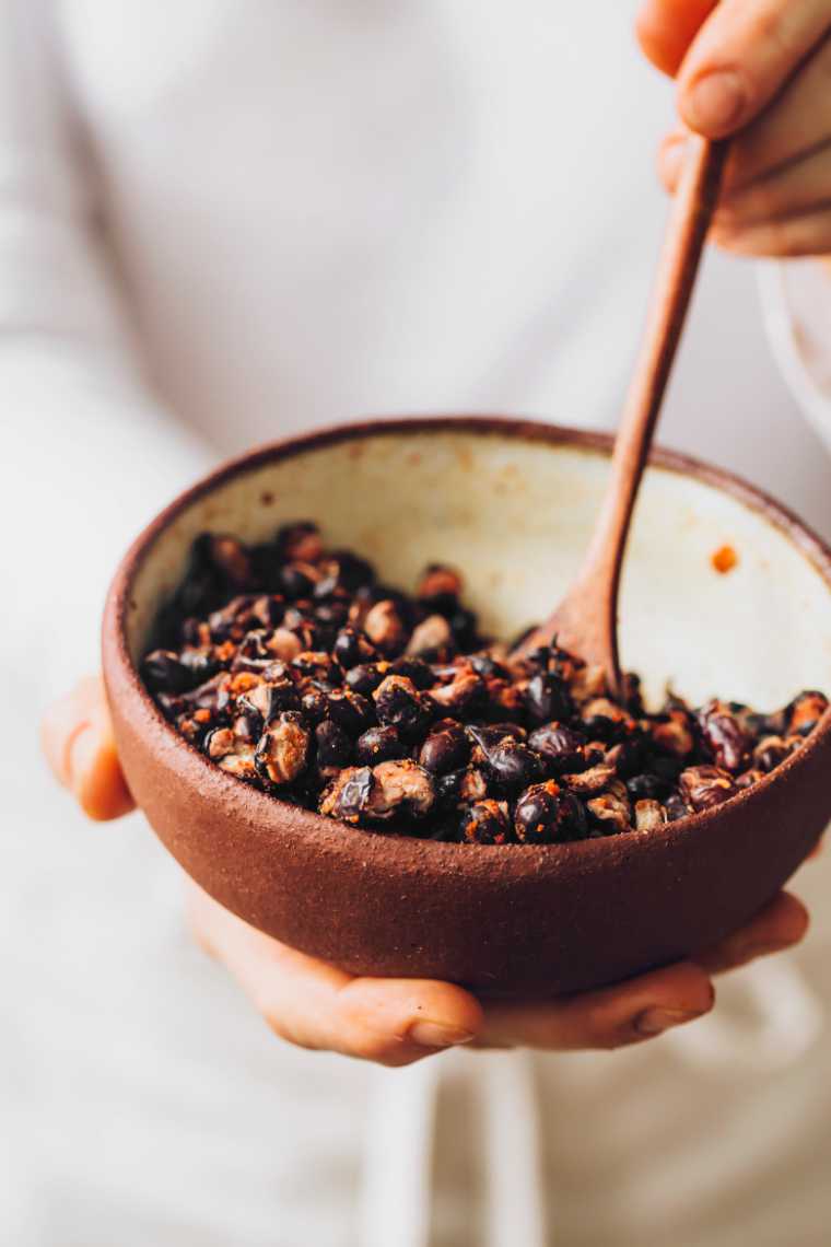 woman holing a bowl of oil-free spicy roasted black beans
