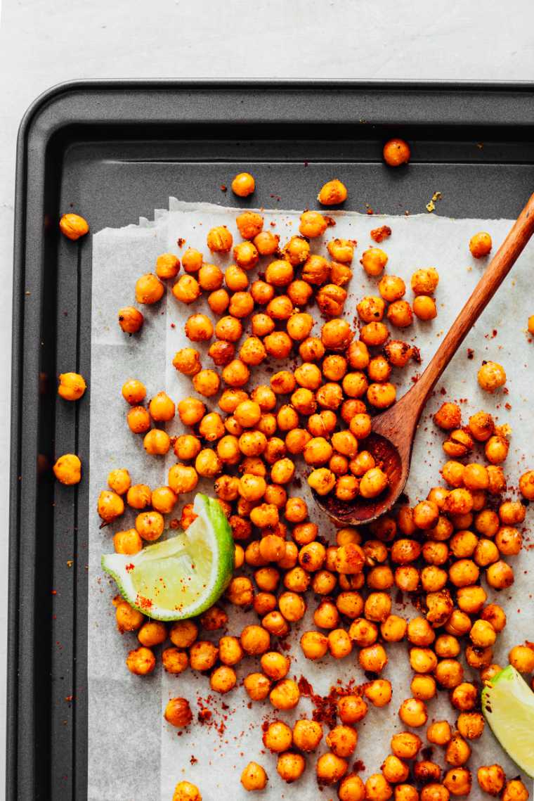 black baking sheet with parchment paper and spicy oil-free roasted chickpeas