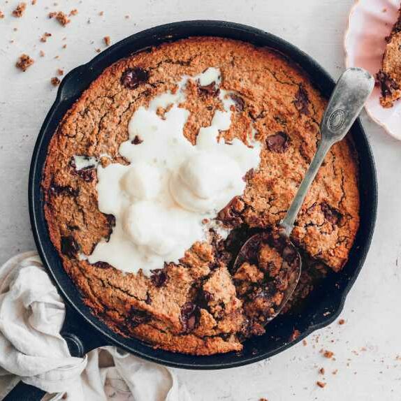cast iron skillet with homemade vegan cookie cake and ice cream on a table