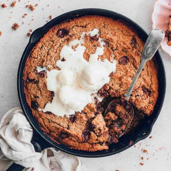 cast iron skillet with homemade vegan cookie cake and ice cream on a table
