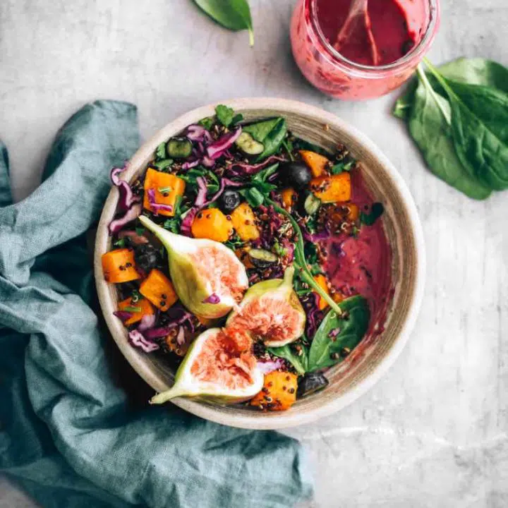 grey bowl with colorful vegan spinach fig salad and an oil-free blueberry dressing