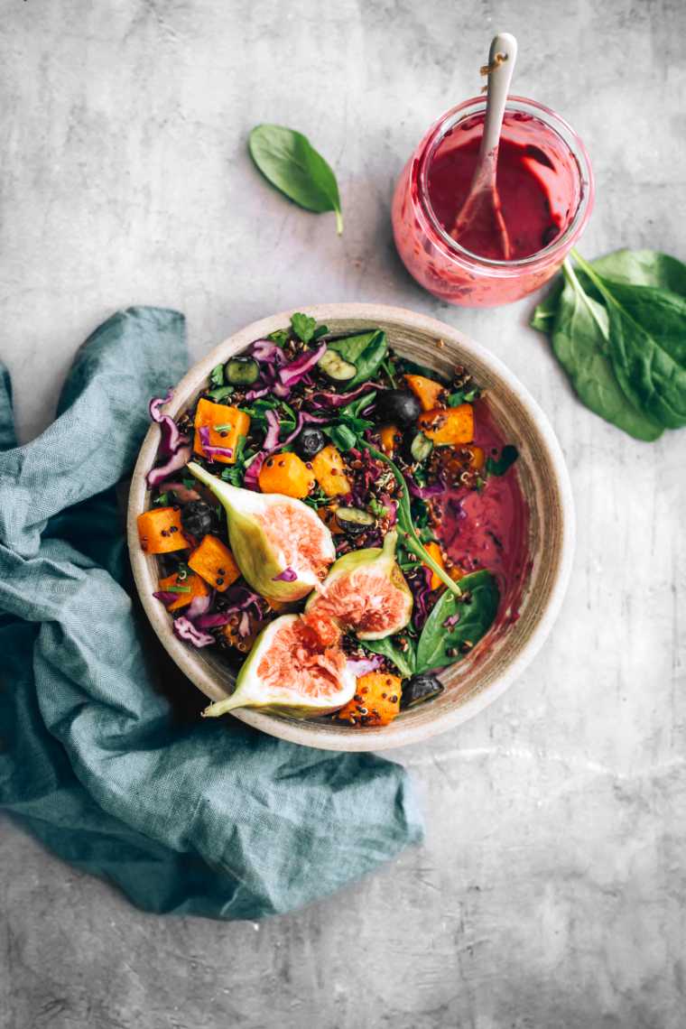 grey bowl with colorful vegan spinach fig salad and an oil-free blueberry dressing