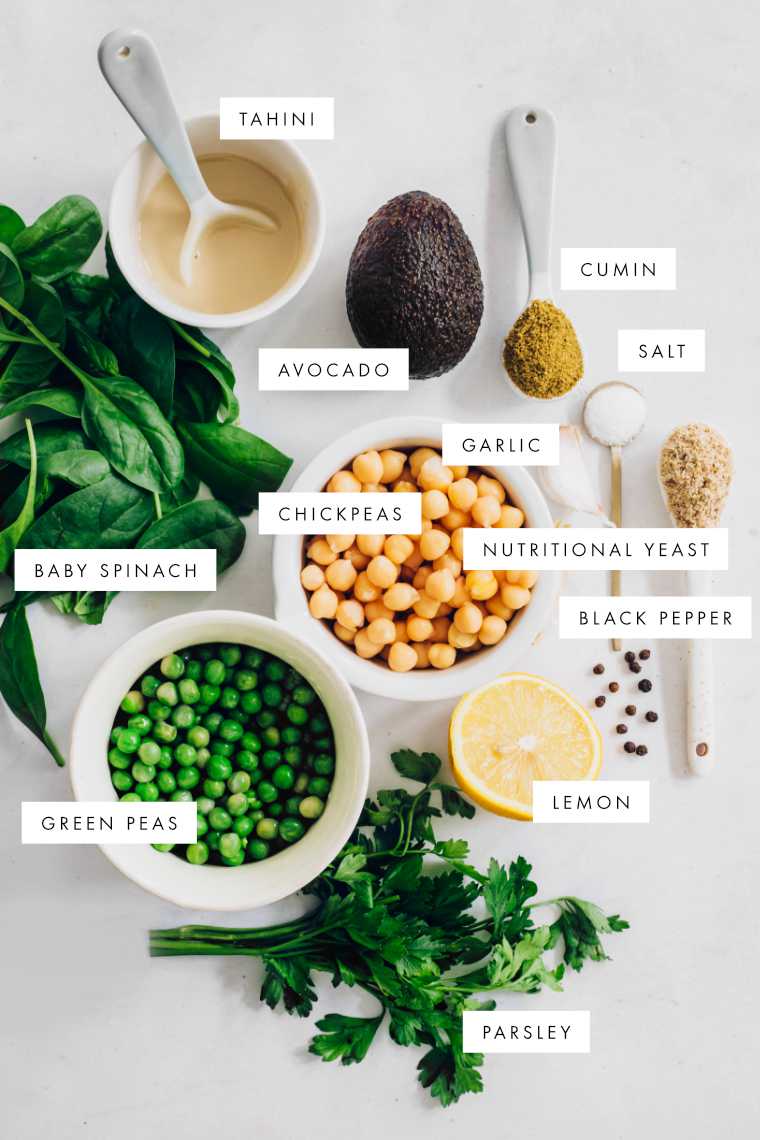 table with tahini, baby spinach, green peas, parsley, chickpeas, avocado, lemon and spices