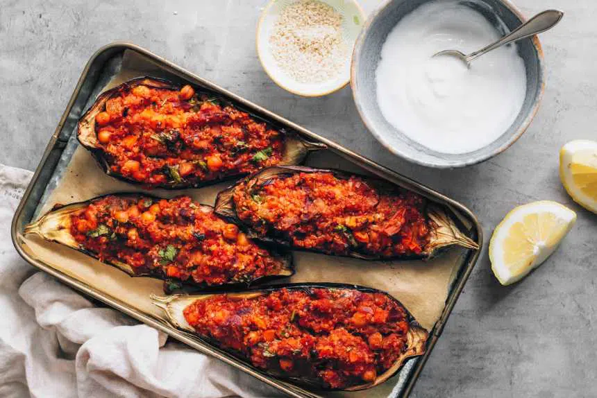 baking dish with four eggplant halves filled with red seasoned quinoa mixture