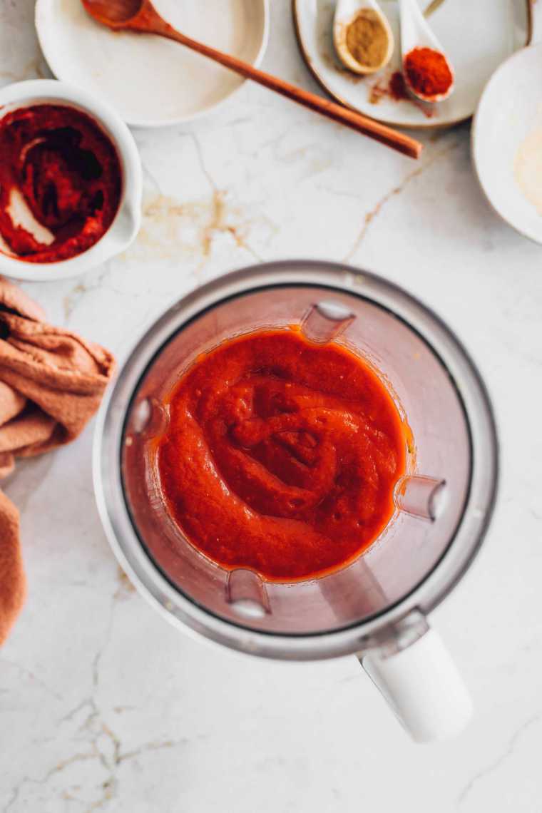 tomato paste in blender next to spices on a table