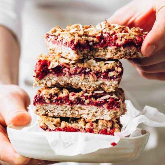 woman holding a white plate with four sugar-free vegan flapjacks on top of each other