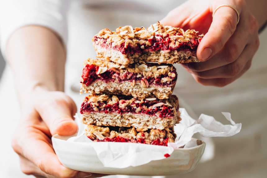 woman holding a white plate with four sugar-free vegan flapjacks on top of each other