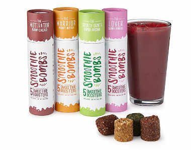 four rolls of different colored papers saying "smoothie bombs" next to a glass of dark red smoothie