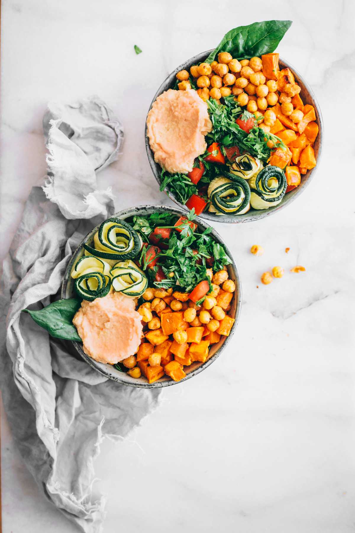 two bowls with chickpeas, salad, zucchini, hummus and sweet potatoes