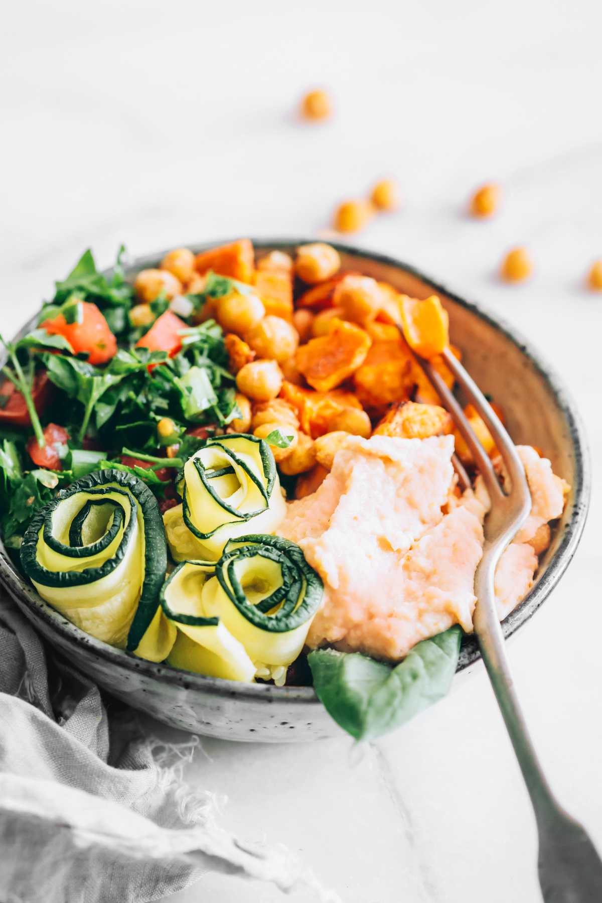 bowl of greens, sweet potatoes, chickpeas and hummus with a fork