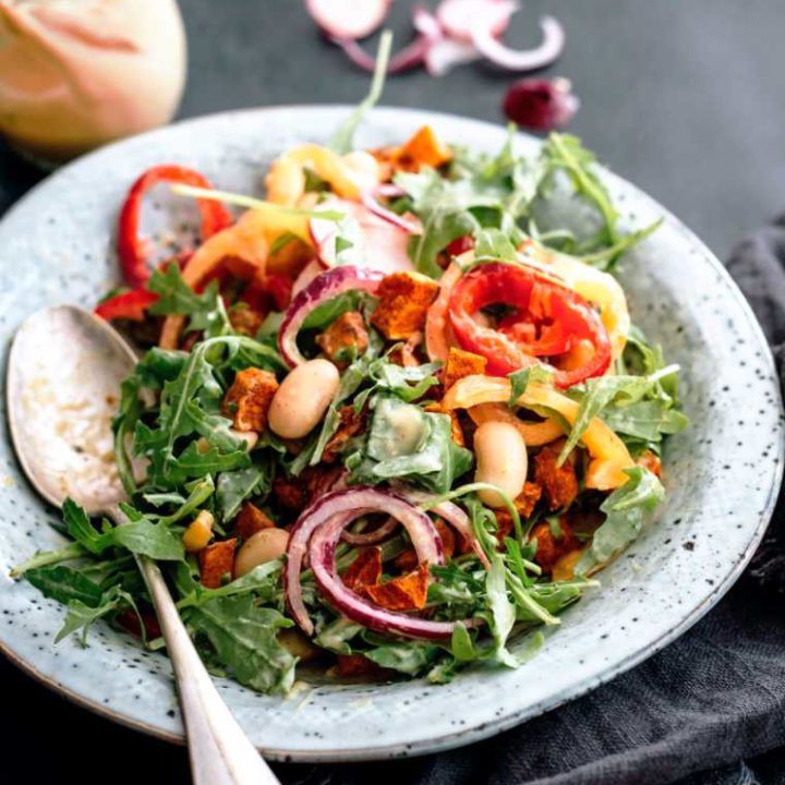 white bowl with vegan sweet potato lima bean and rocket salad next to a spoon