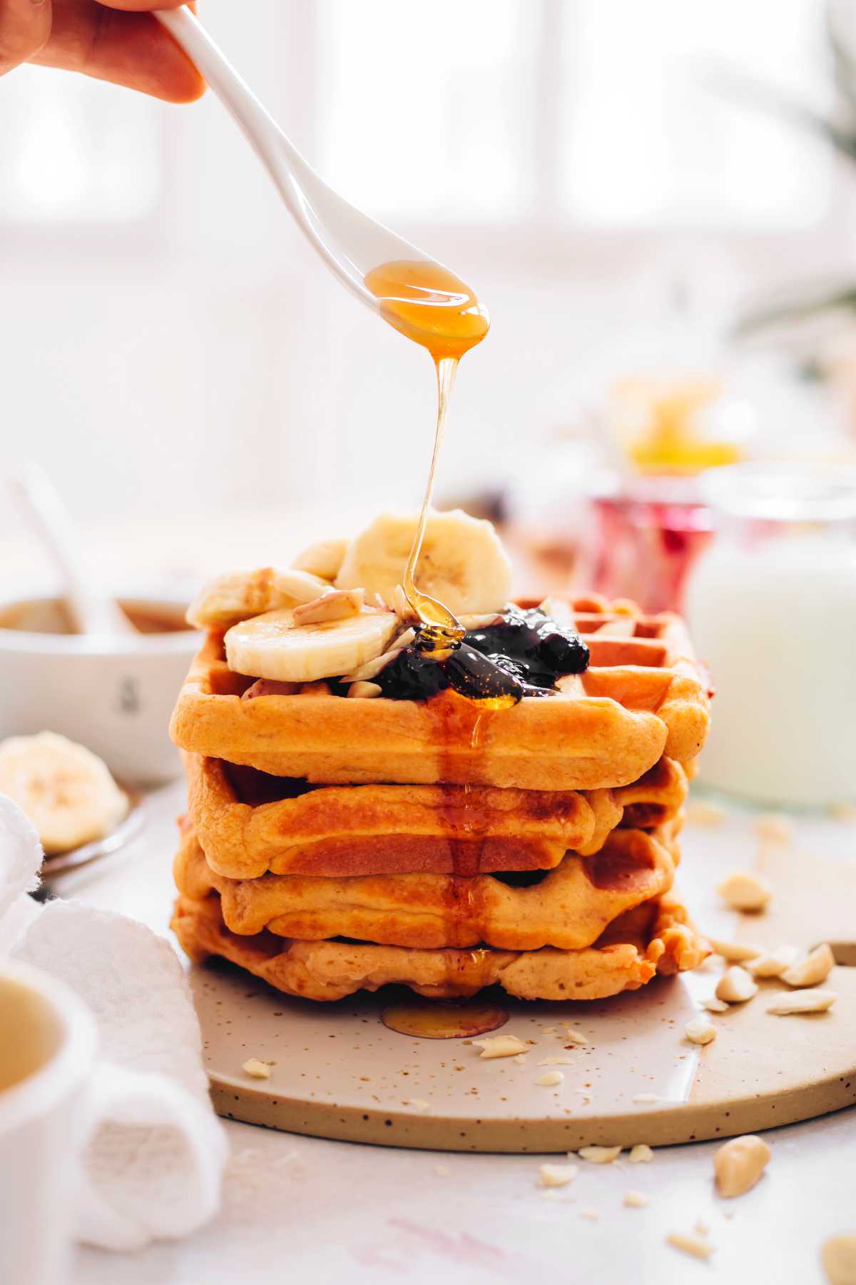 vegan sweet potato waffles being drizzled with maple syrup