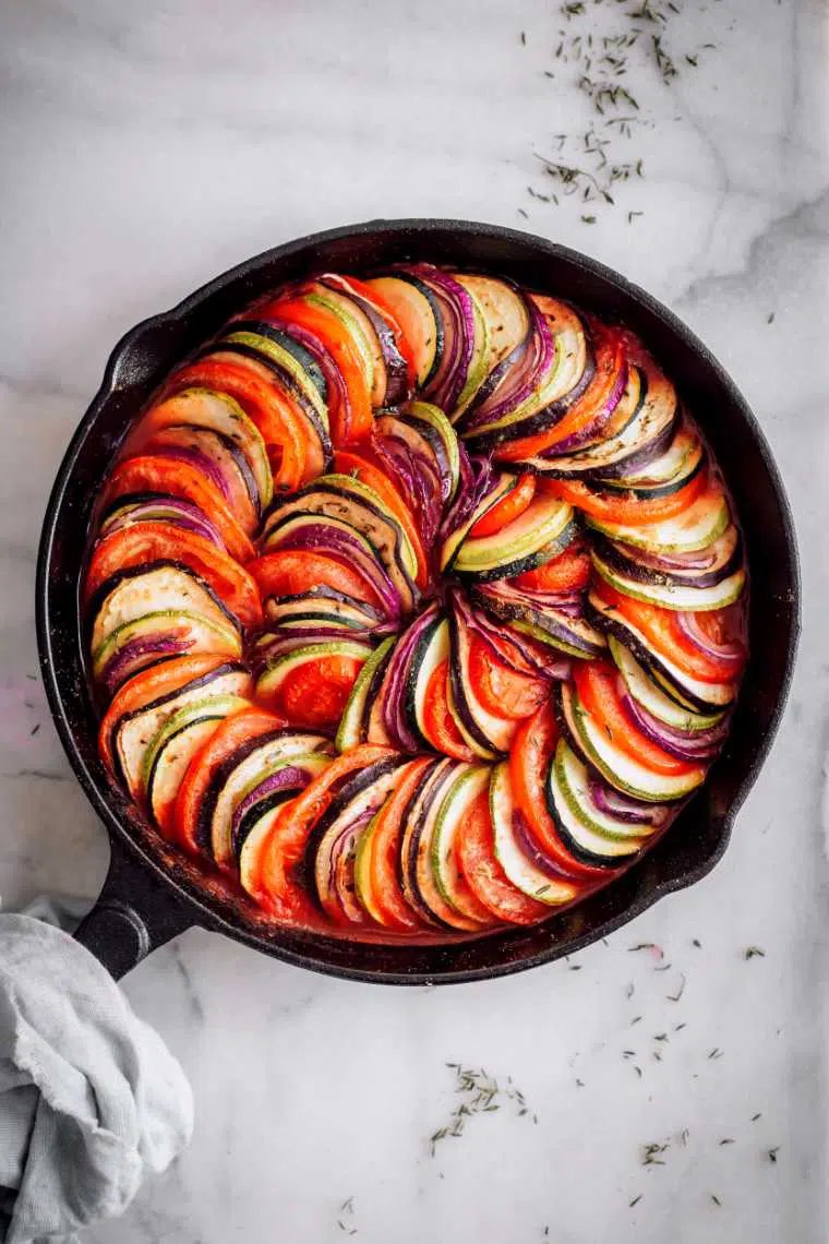white table with cast iron skillet containing colorful Vegan Tian Ratatouille