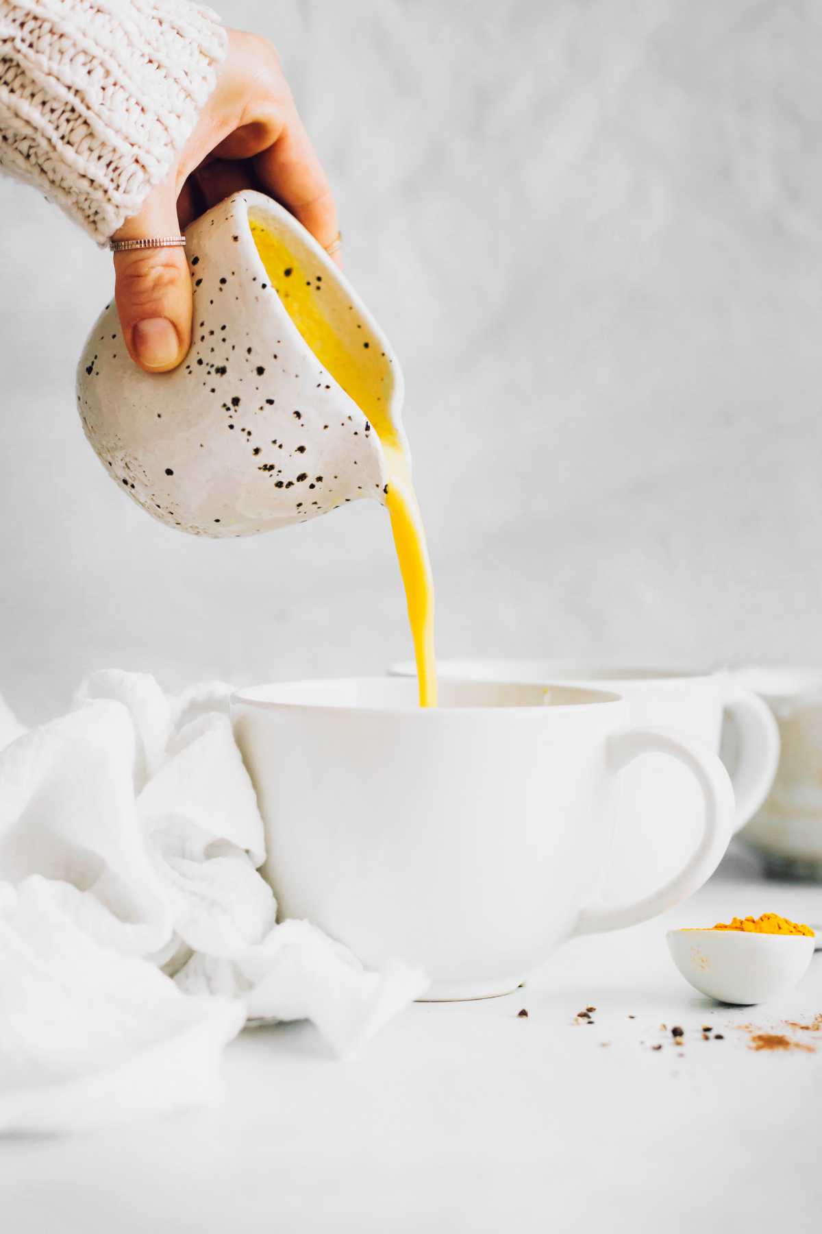 hand pouring golden milk into mugs