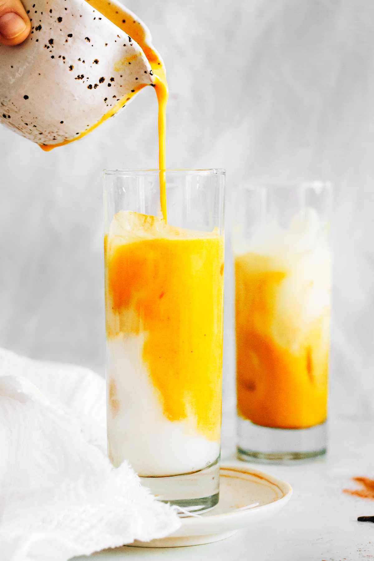 pouring golden milk into ice cubes in glasses