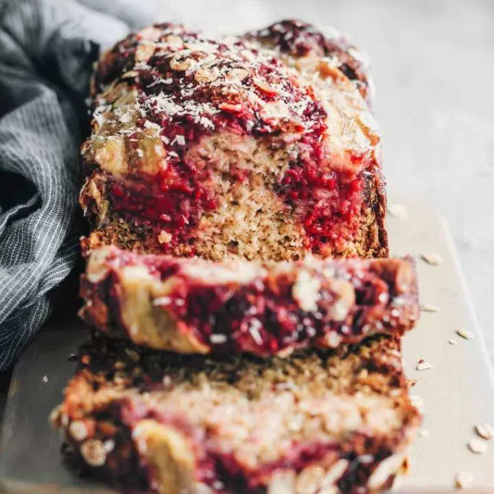 Slices of Vegan Banana Bread with raspberries on cutting board