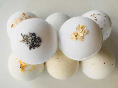 eight white vegan bath bombs with different toppings like oats or flax