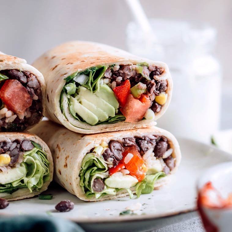 Close up of four colorful vegan burritos filled with avocado, rice and tomatoes